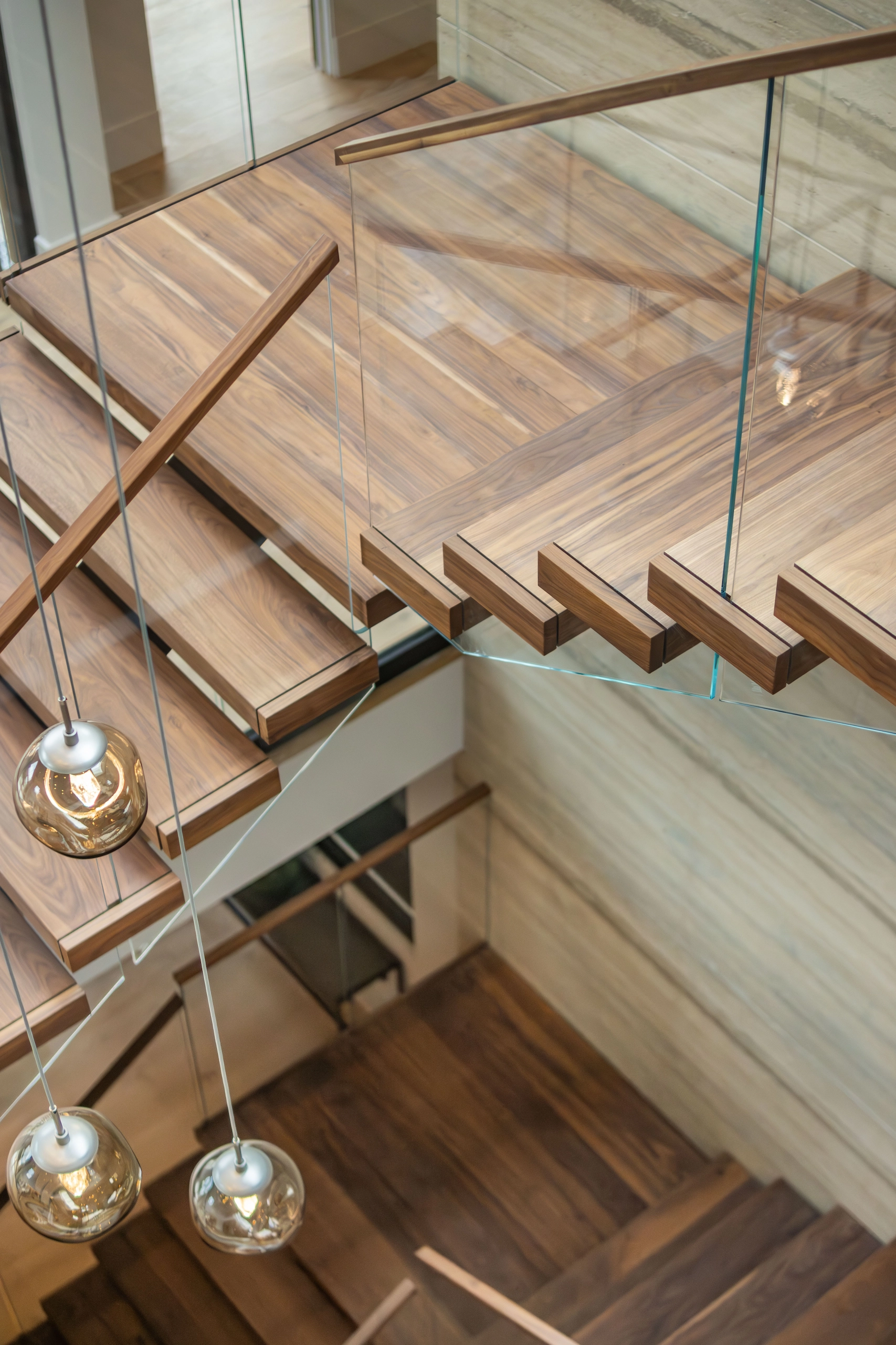 Walnut treads and a wood-capped glass railing seen from above on a FLIGHT Mono stair
