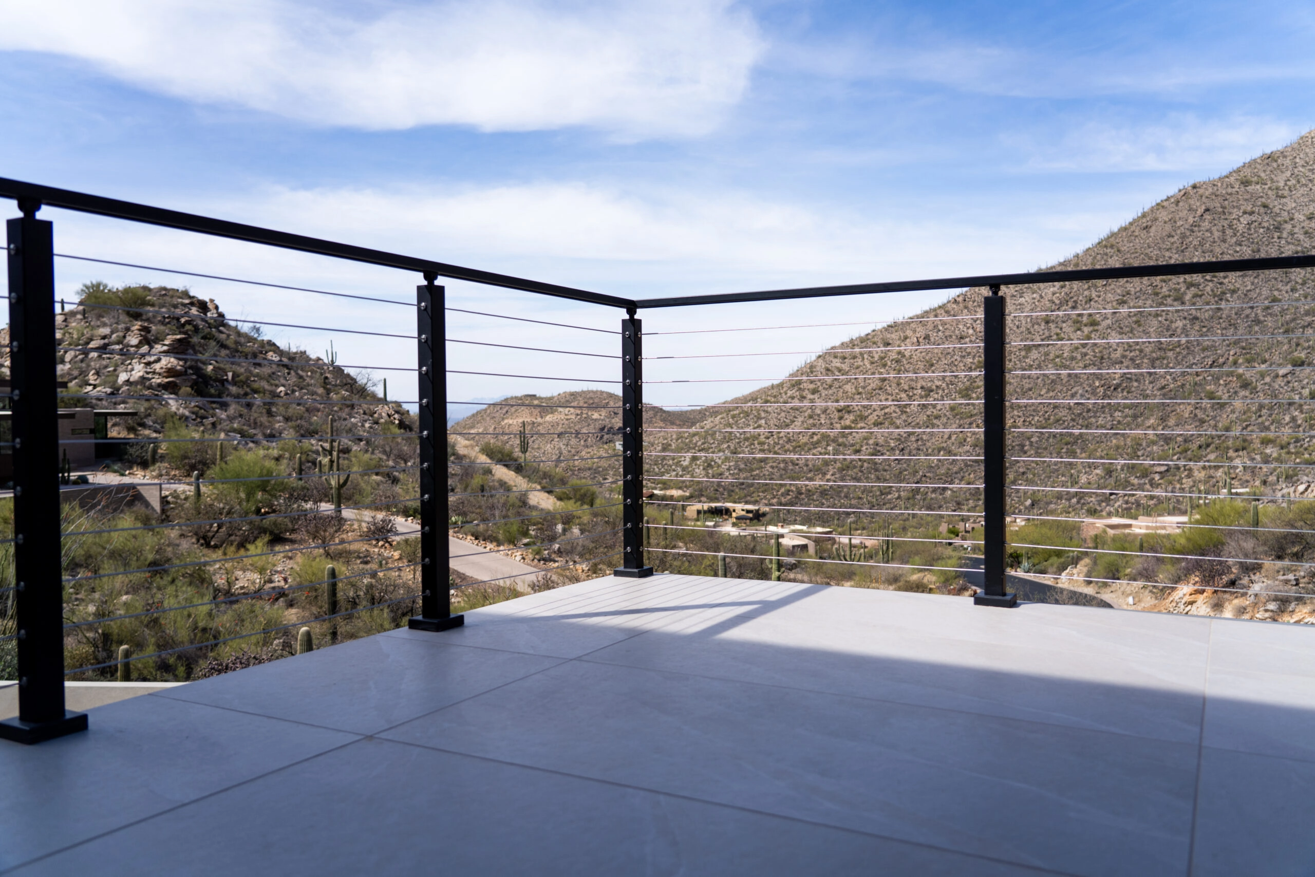Terraced hills and saguaros framed by the corner post of black Signature Cable railing