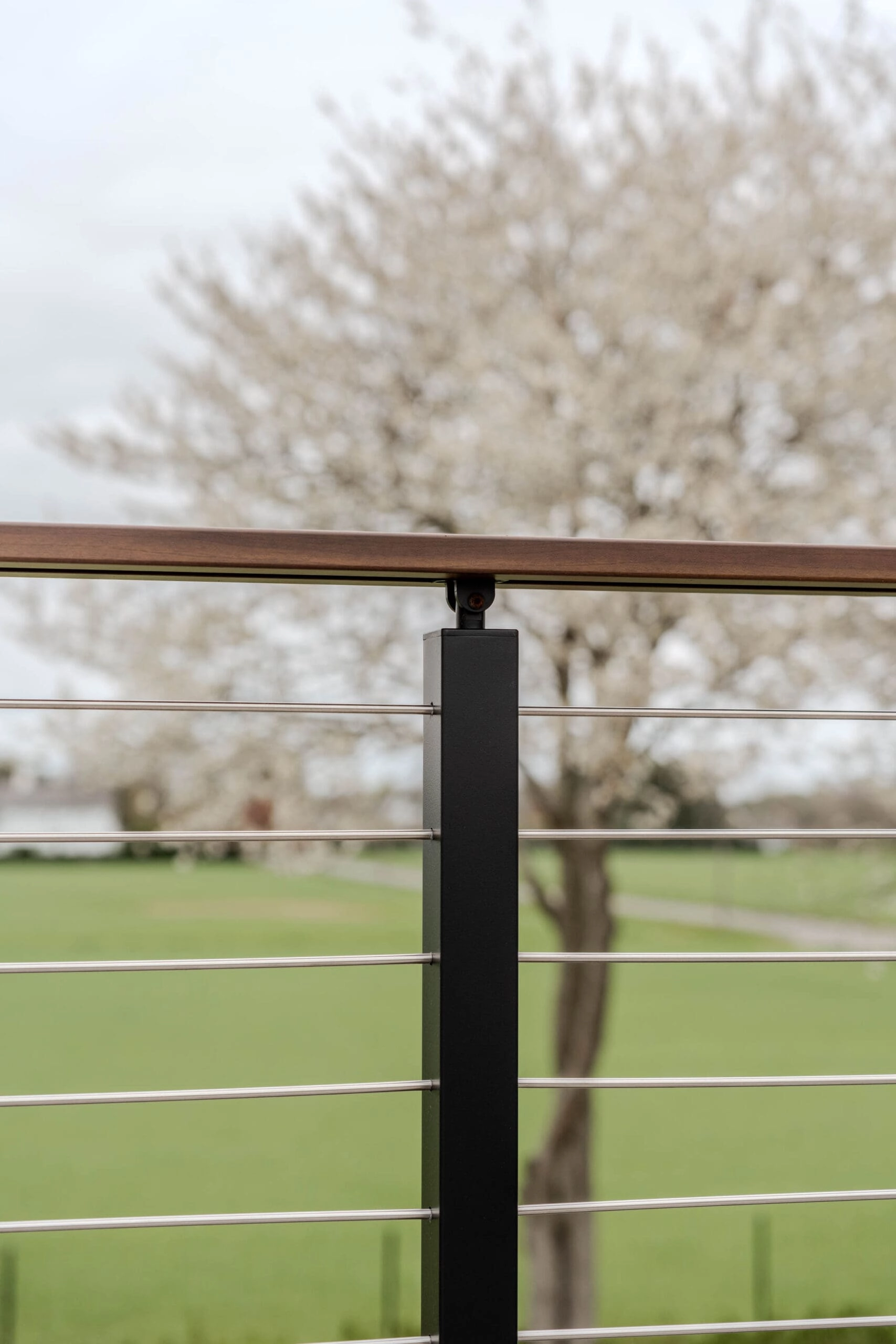 Stainless rods terminate into a black Signature Rod post beneath a wood top rail