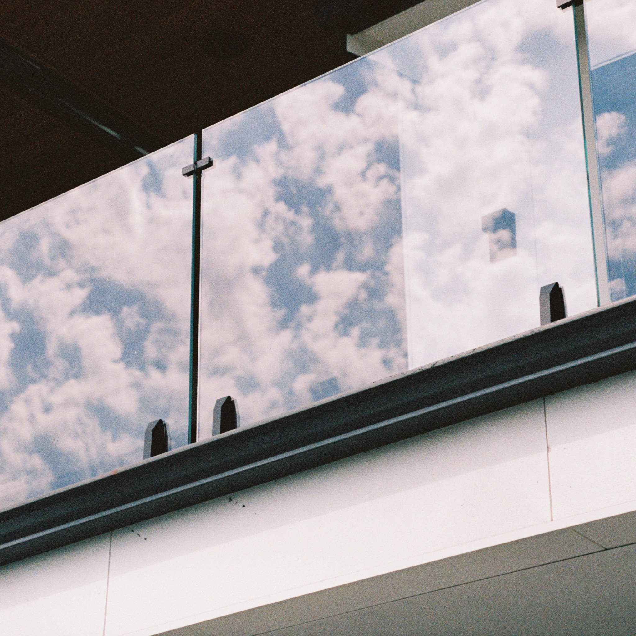 Cloud reflected in glass panels held by black Talon Spigots along a black base rail