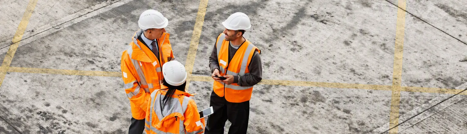 Trois collaborateurs en tenue haute visibilité échangeant sur un chantier