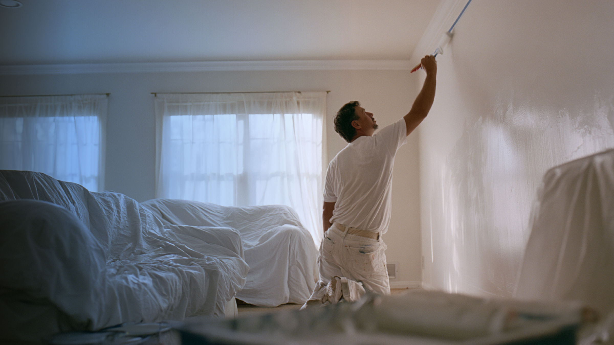 Painter cutting in a ceiling line in a residential living room