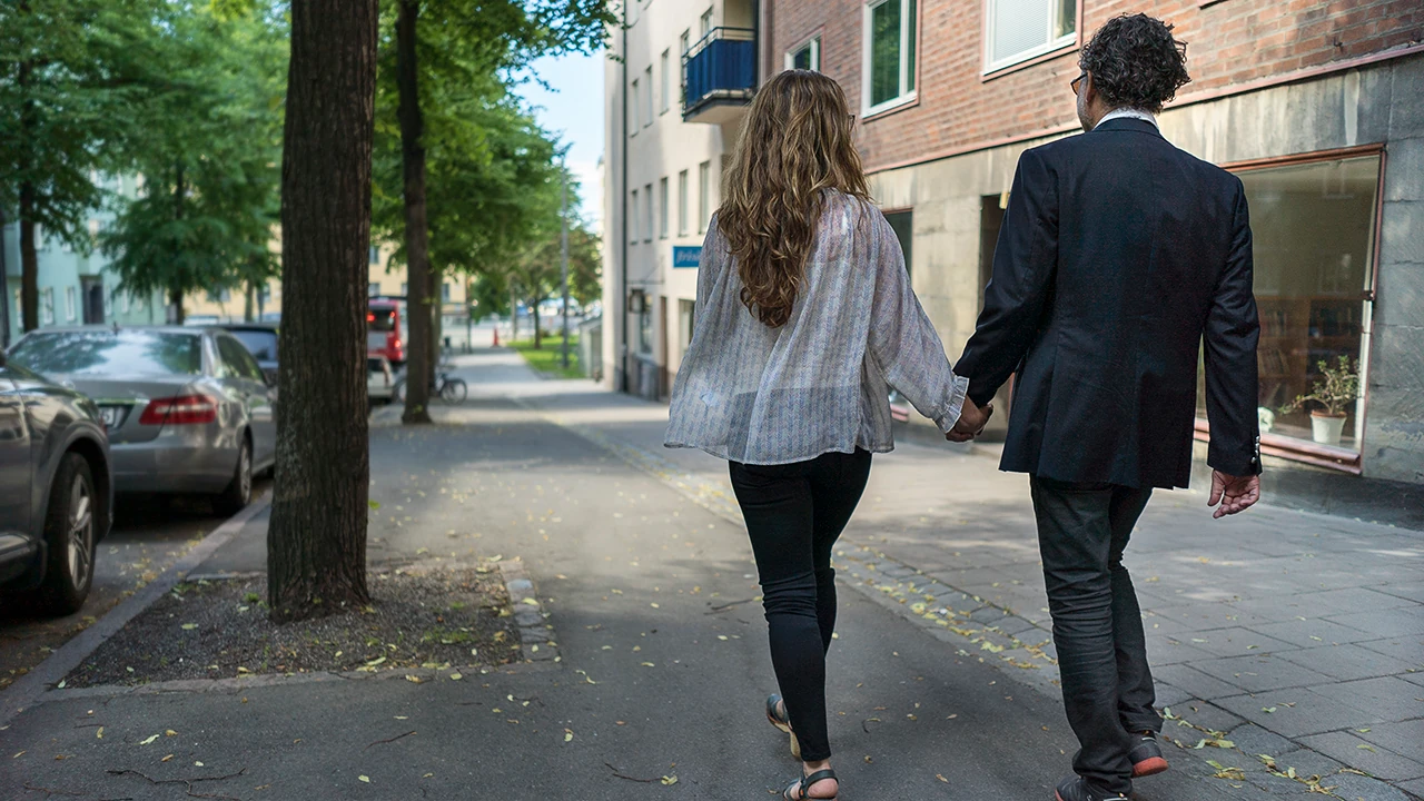 Par som promenerar på en trottoar i Stockholm