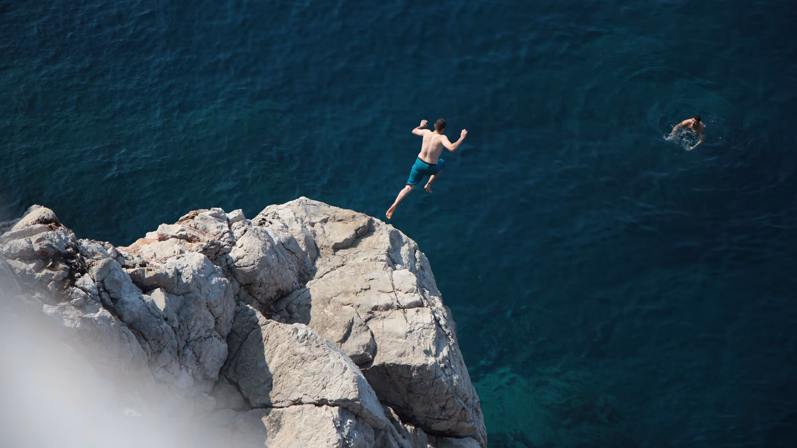 A person cliff diving into blue water.