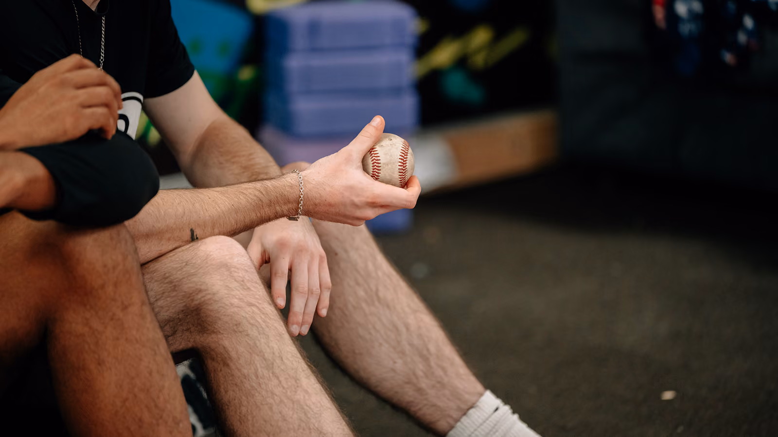 An athlete sitting down holding a baseball.