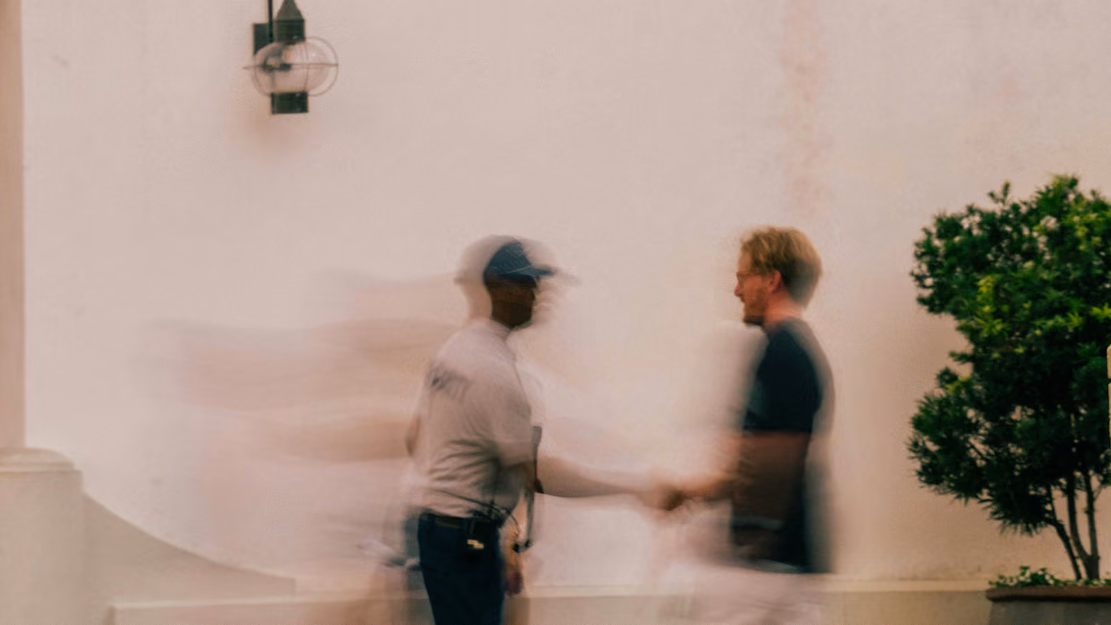 A blurred image of two men walking past each other.