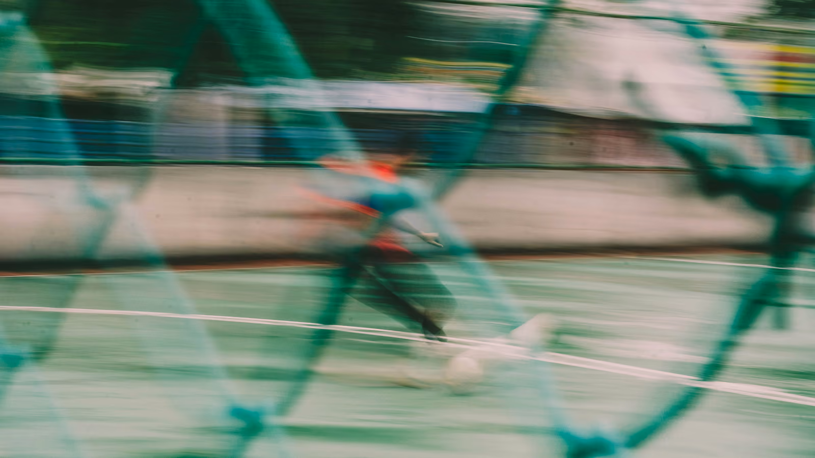 Blurry baseball player behind fence.
