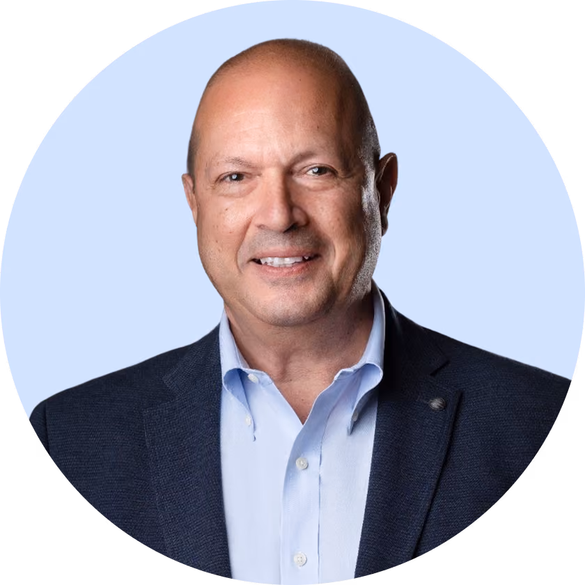 Portrait of a smiling bald man wearing a navy blazer and light blue collared shirt.