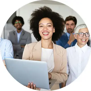 A woman smiling holding a laptop with people around her