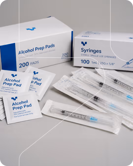 Boxes of alcohol prep pads and syringes with individually wrapped alcohol pads and syringes on a surface.