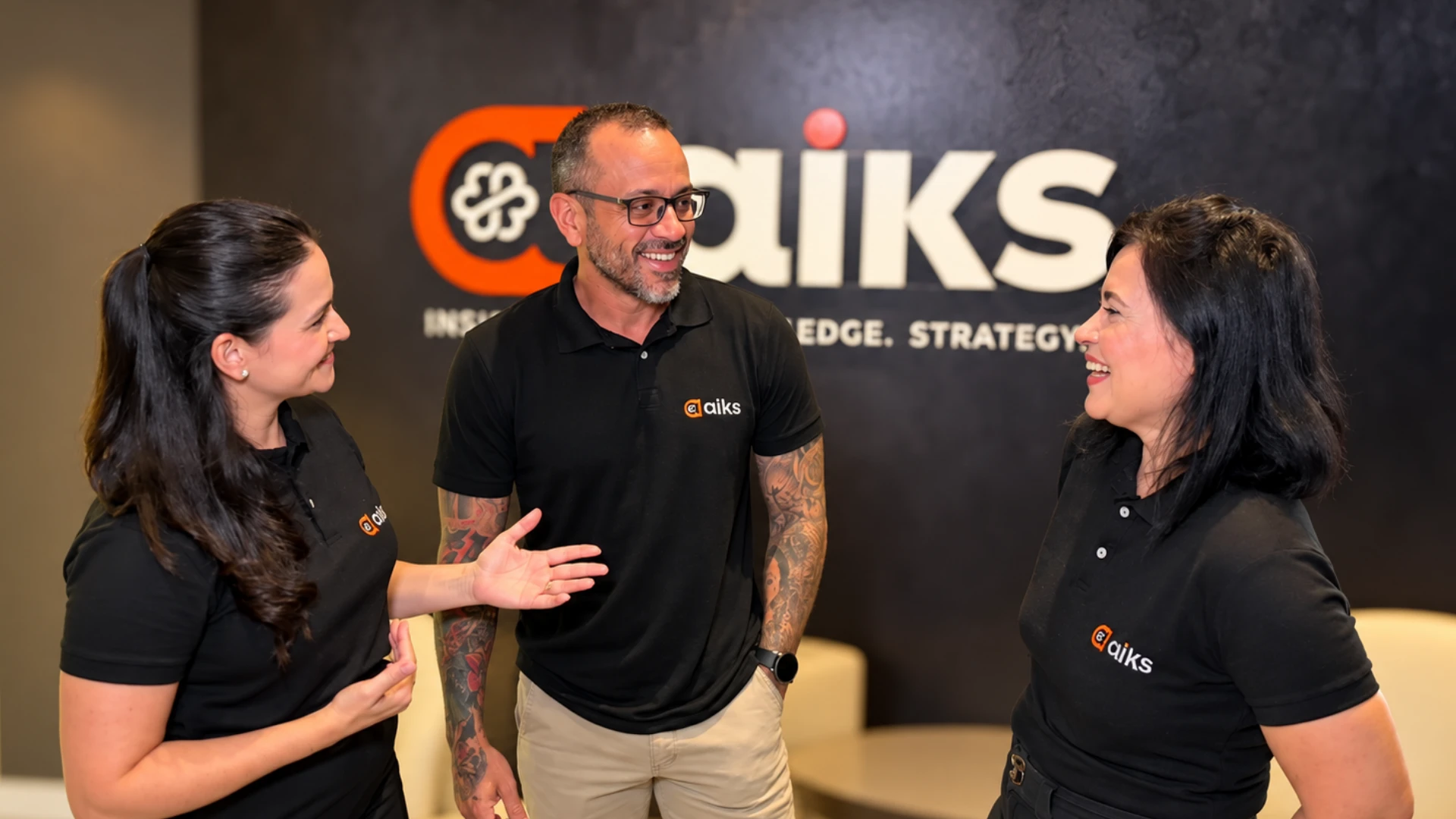 Equipe da AIKS conversando na recepção, em frente ao logo da empresa