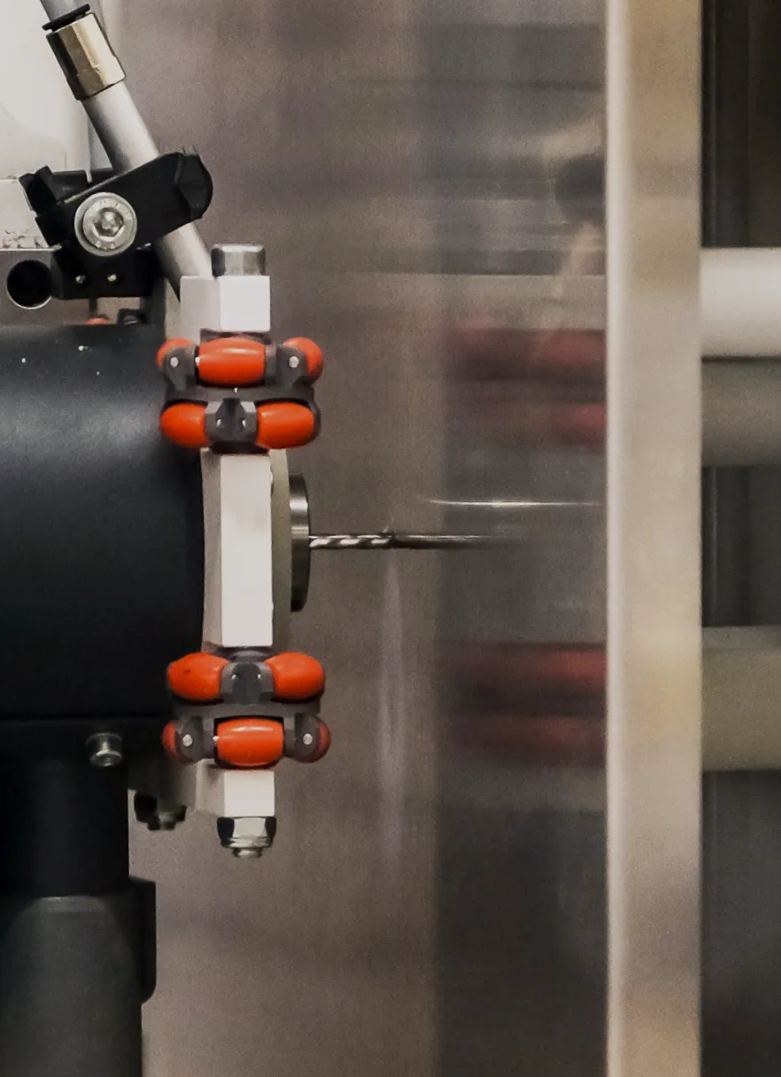 Automated CNC machine drilling precise mounting holes into a stainless steel control panel enclosure during fabrication.