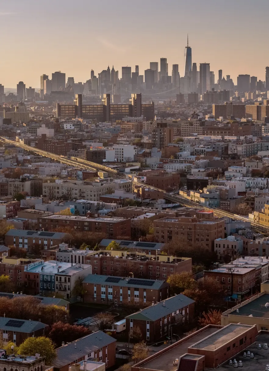 Brooklyn cityscape at sunset with the Lower Manhattan skyline, where Podium Automation is based.