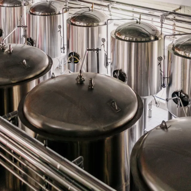 Stainless steel fermentation tanks in a brewery, a food and beverage process Podium Automation automates with control panels.
