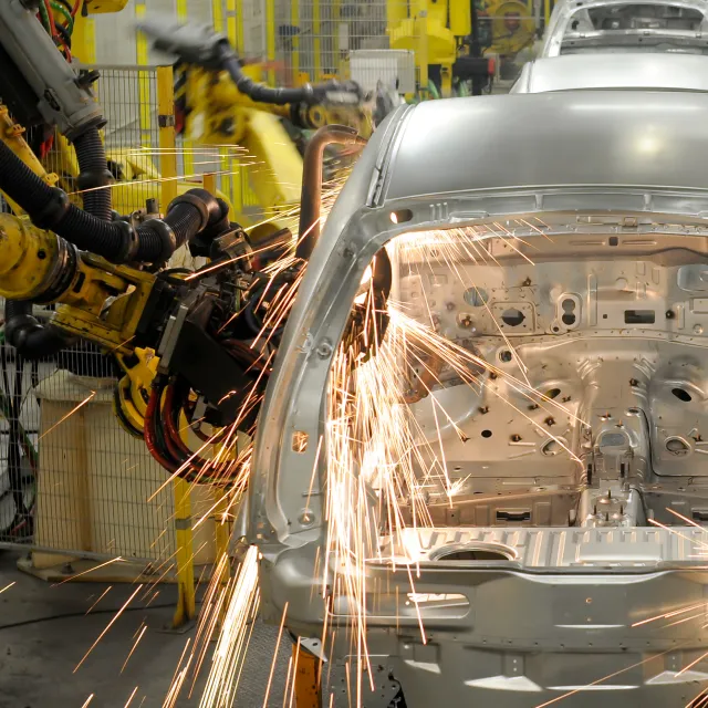Robotic arms welding a car body on an automotive assembly line that depends on custom control panels.