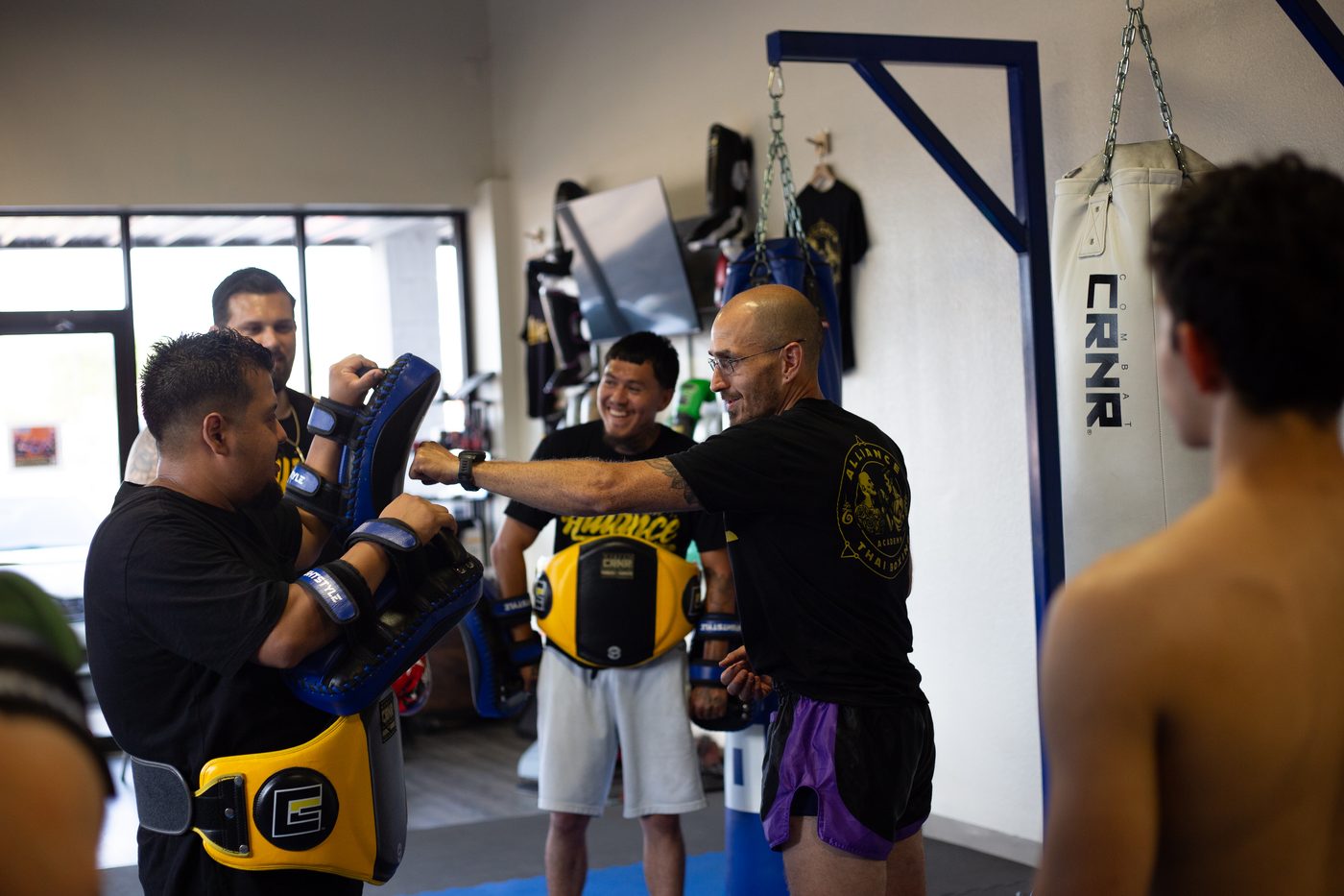 Coach and members smiling during Muay Thai pad work at Alliance Thai Boxing Academy in Cedar Park, TX
