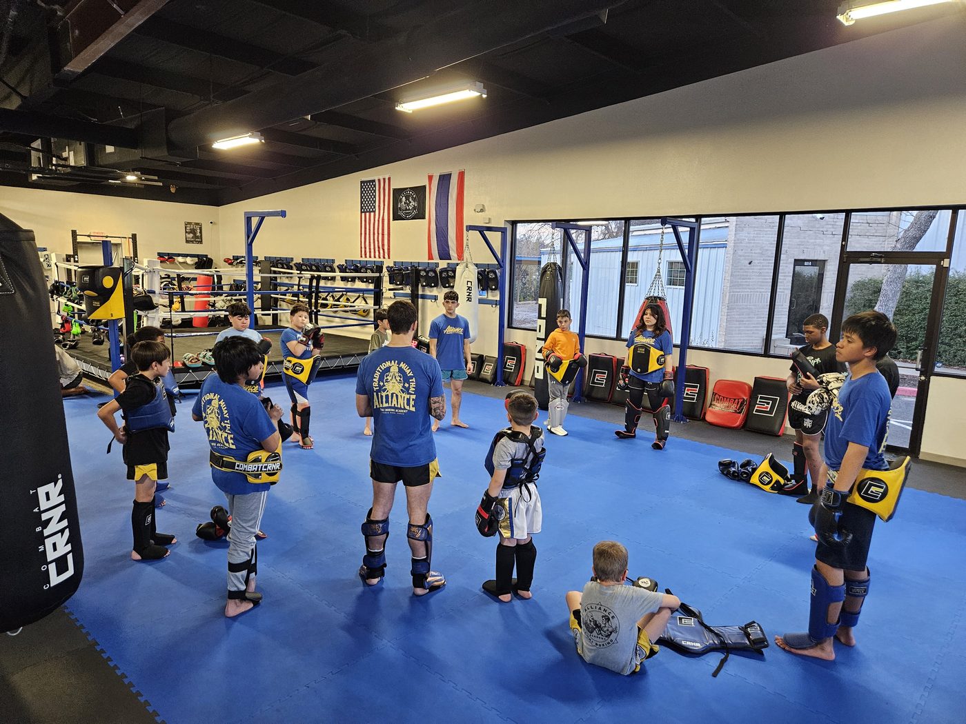 Kids gathered in a circle around their coach during Muay Thai class at Alliance Thai Boxing Academy