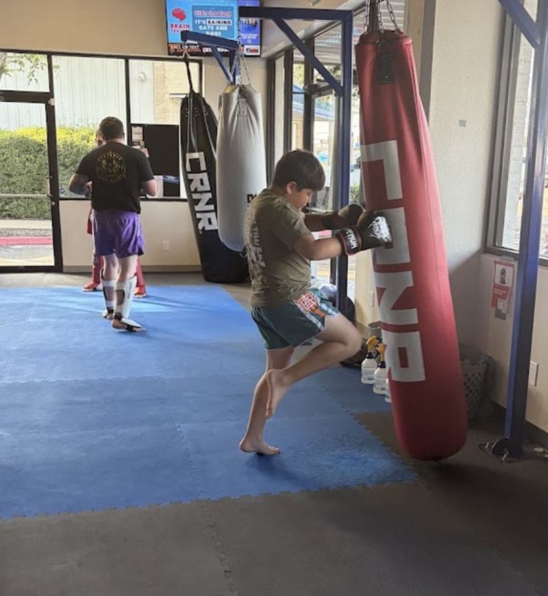 Boy throwing a knee on the heavy bag during kids Muay Thai class at Alliance Thai Boxing Academy