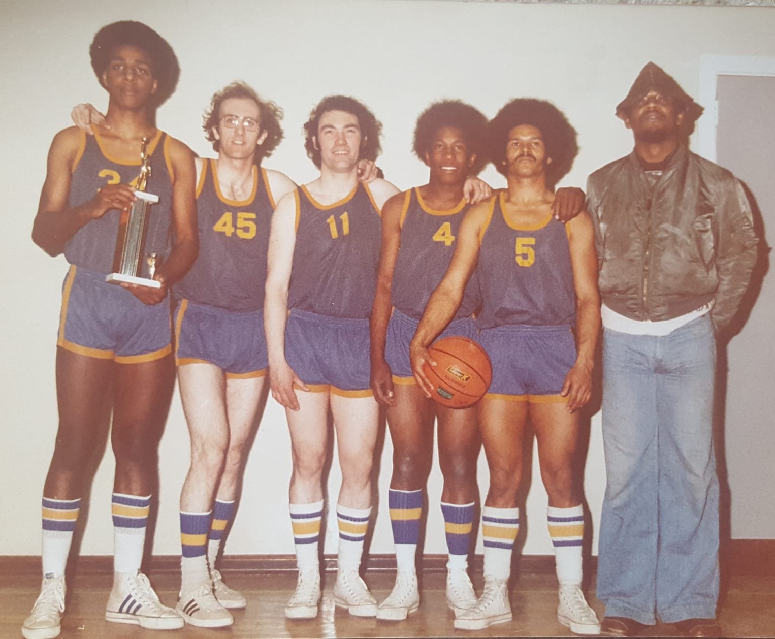 An early Topcats squad in blue and gold vests with a trophy