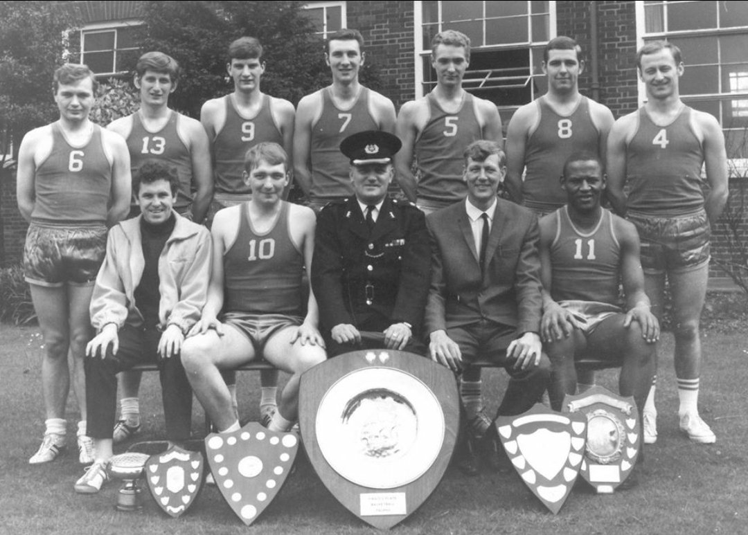 A Topcats team with a table of shields and trophies, black and white
