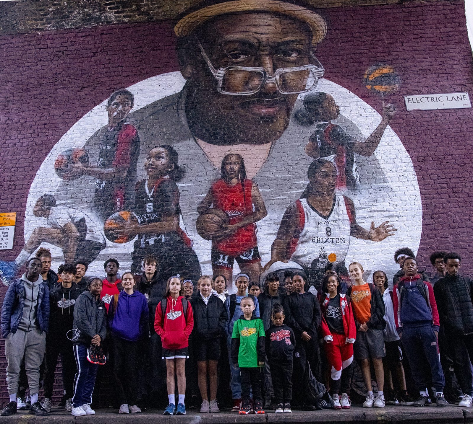The Brixton community in front of the Jimmy Rogers mural