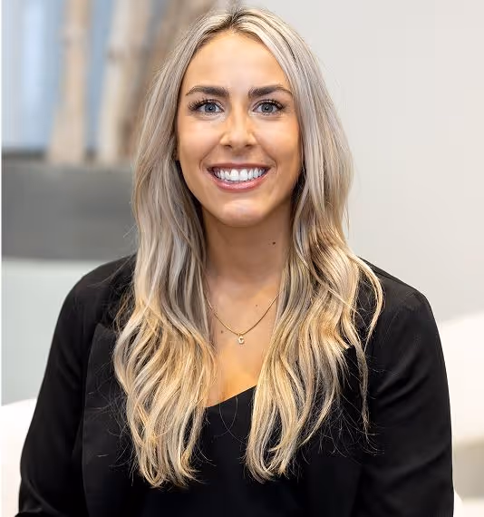 A smiling young woman with long blonde hair wearing a black blazer.