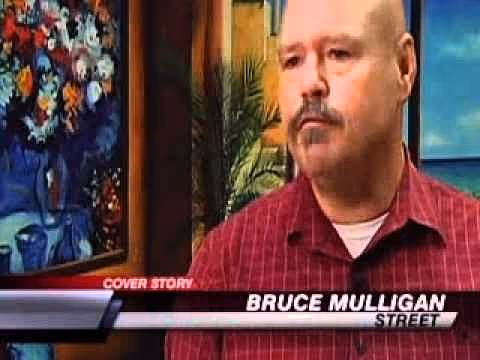 An image of a man with a mustache and bald head, wearing a red checkered shirt, speaking in front of a colorful background featuring various paintings and flowers. The text in the foreground reads 'COVER STORY' and 'BRUCE MULLIGAN STREET'.