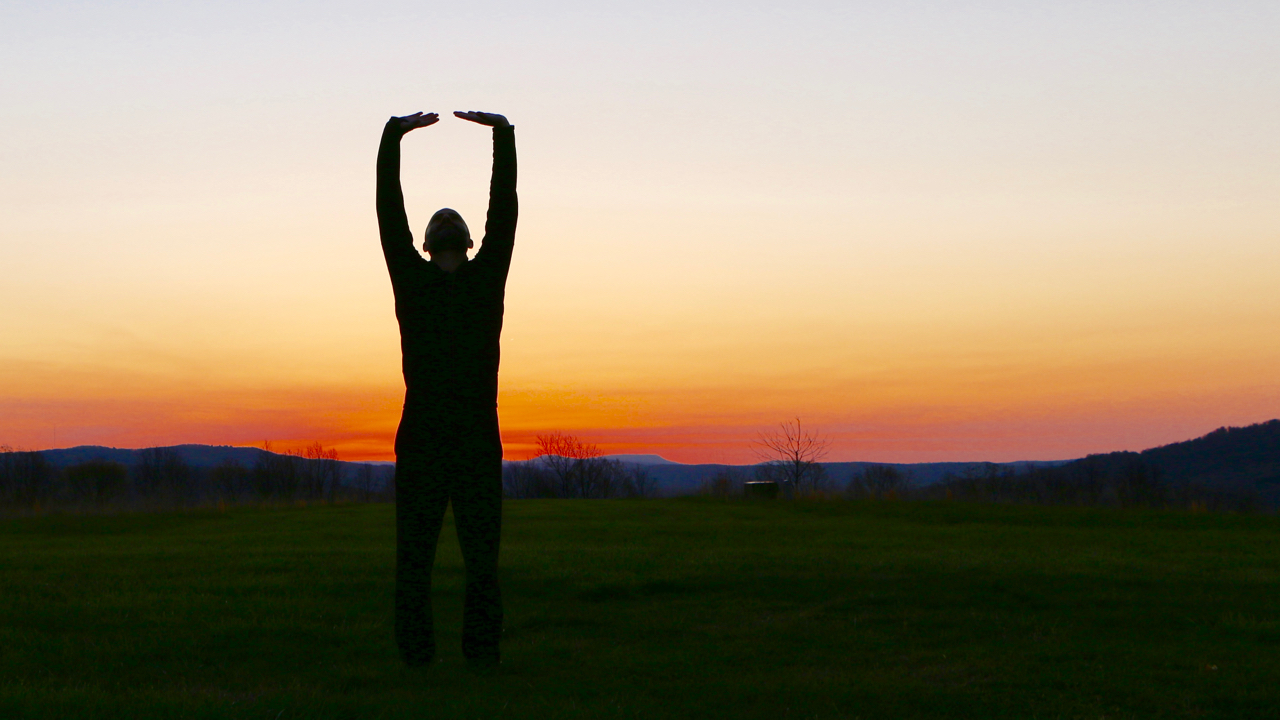 older adult performing touch the sky tai chi move