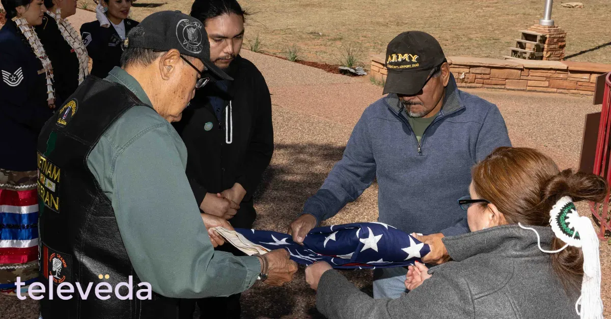 Veterans folding an American flag outdoors, with Televeda logo