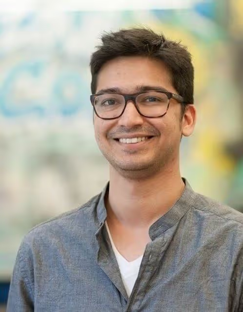 Portrait of a smiling young man with glasses in a gray shirt