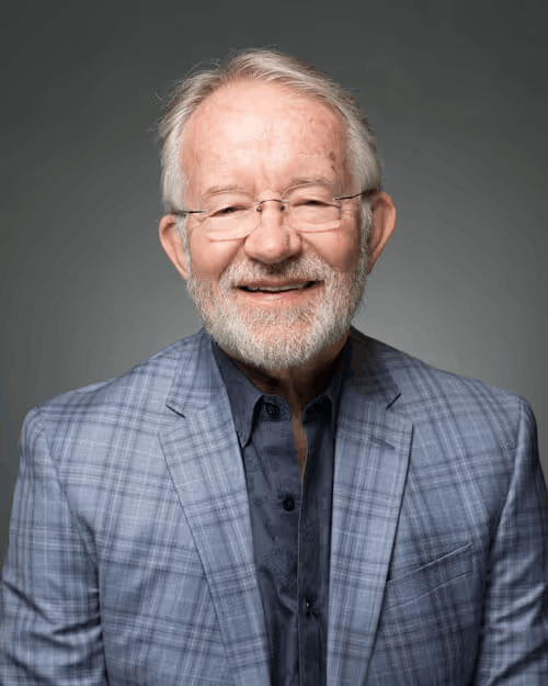 Portrait of an older man with white beard and glasses in a plaid blazer