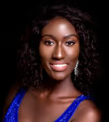 Portrait of a smiling woman with curly dark hair and a blue sparkly top