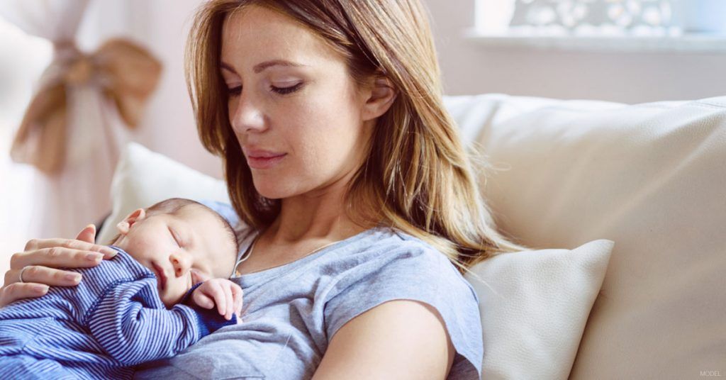 Woman with breast implants holding new baby