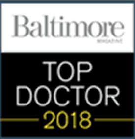 A logo featuring the text 'Baltimore Magazine' in an elegant font at the top, with the words 'TOP DOCTOR' in bold white letters and the year '2018' in a smaller yellow font below.