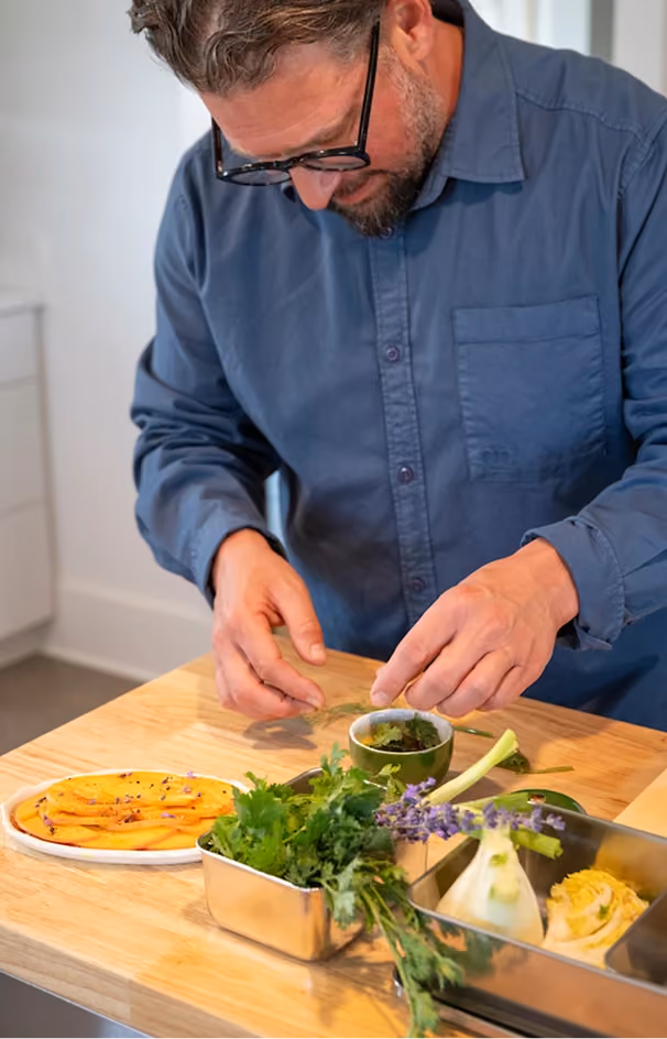 Chef garnishing a dish with fresh herbs, fennel and lavender in the kitchen