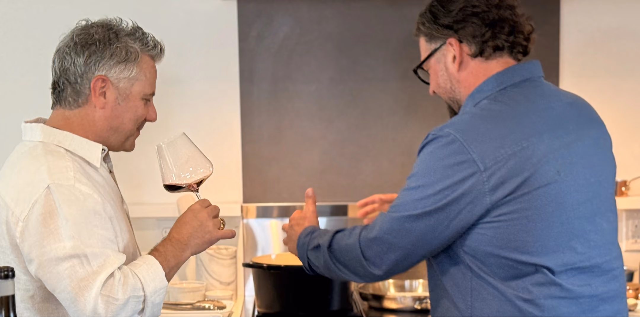 Two guests tasting wine together in the kitchen