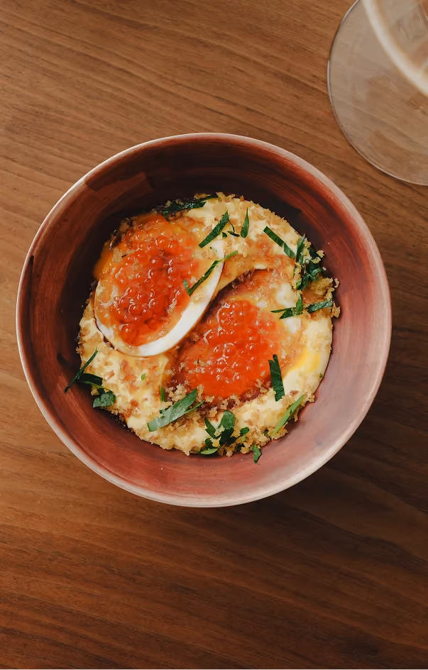 Soft-boiled egg with salmon roe, crispy breadcrumbs and herbs over a creamy base