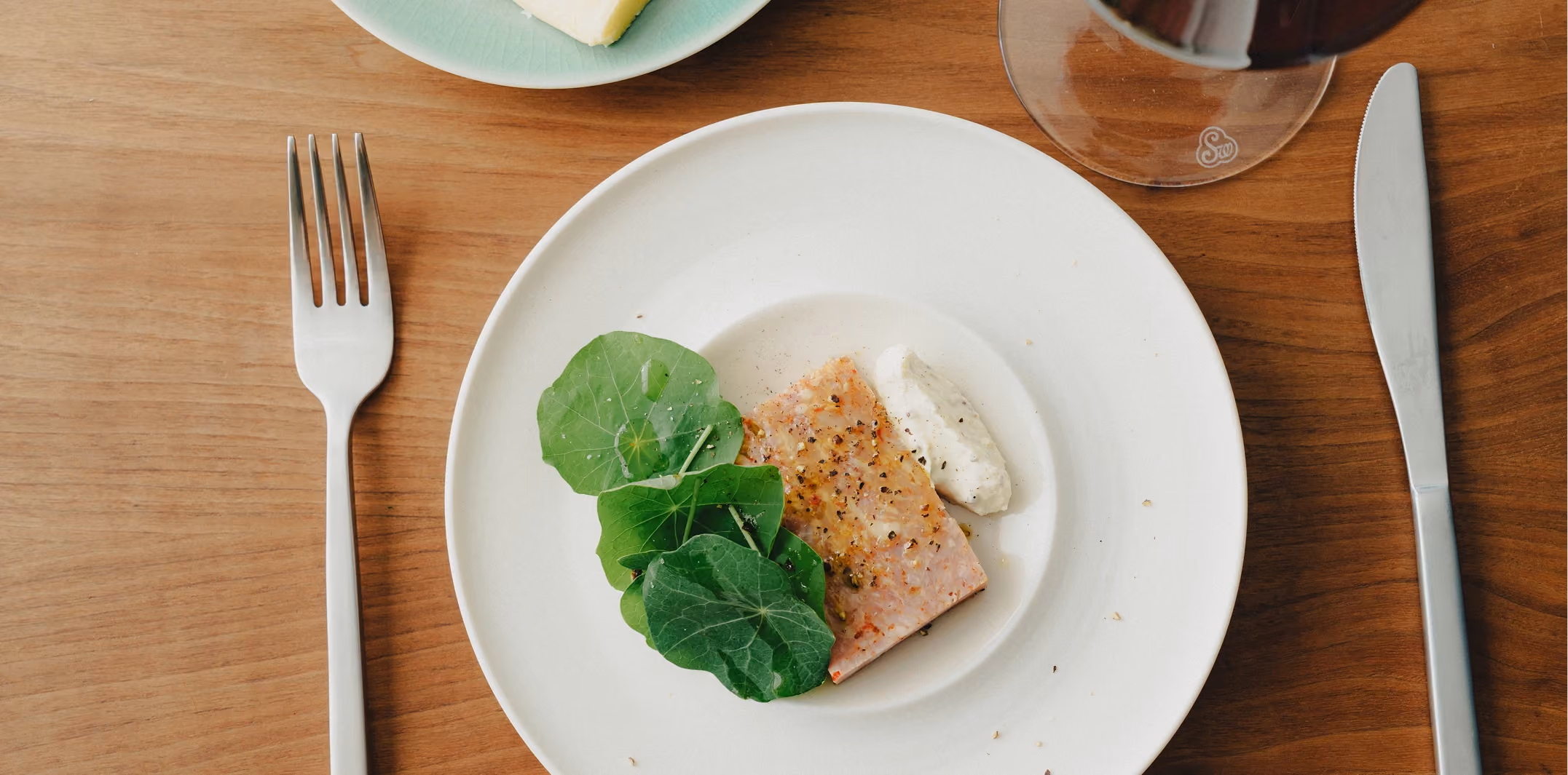 Fish course with fresh greens and a glass of red wine