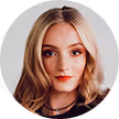 Portrait of a young woman with blonde hair and red lipstick on a gray background.