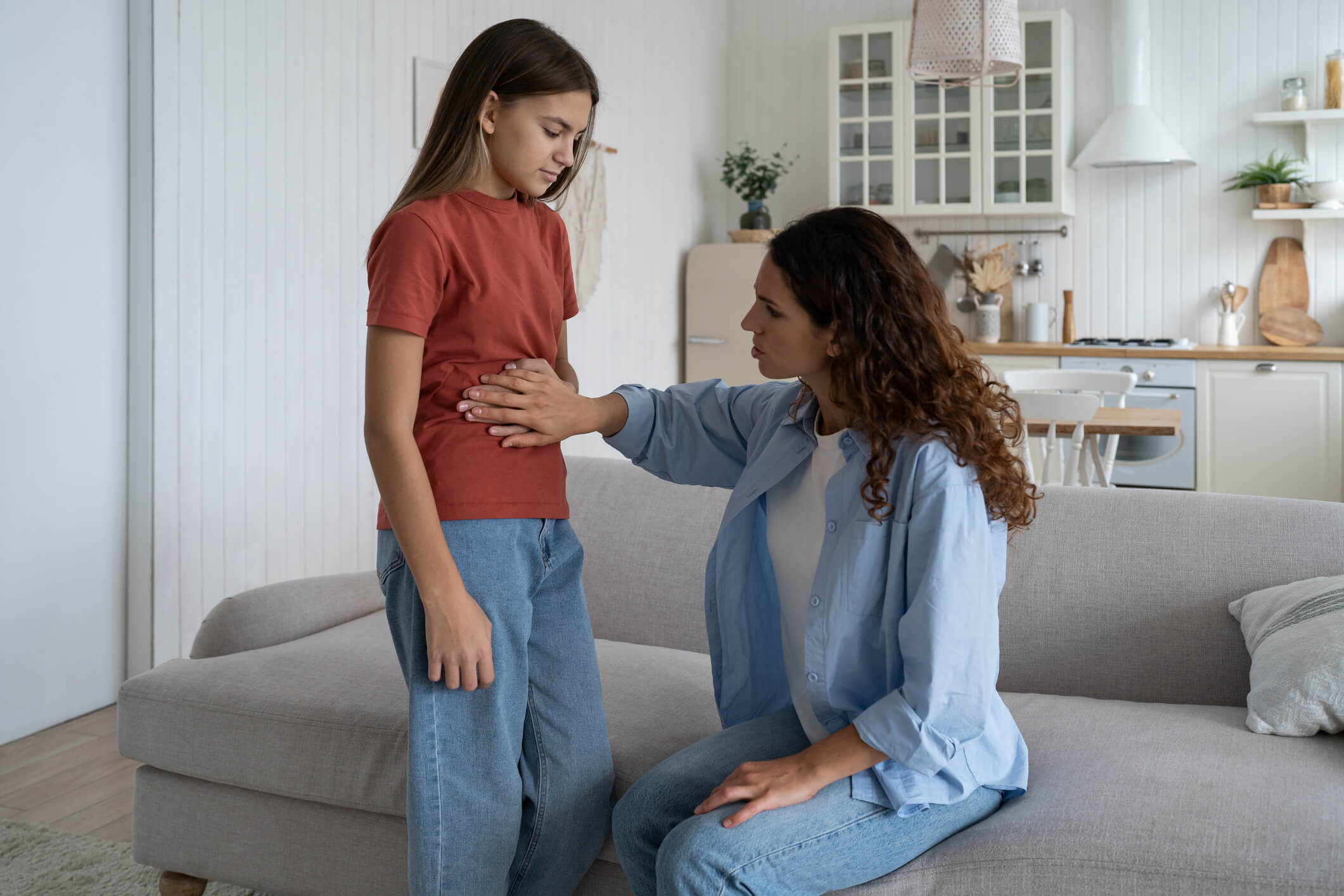 Parent comforting a child with a hand on the tummy