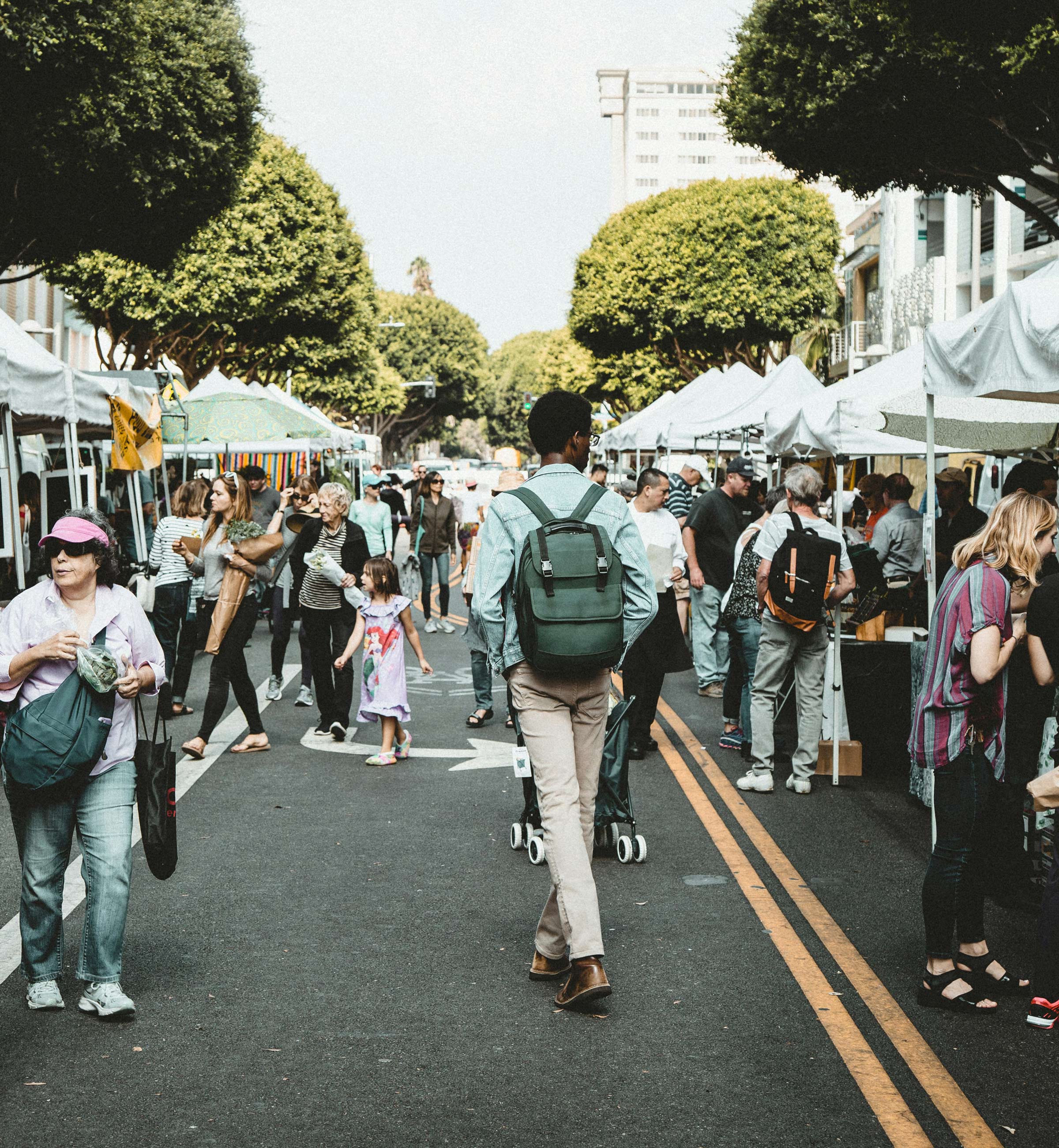 Shoppers walking between stalls at an outdoor farmers market