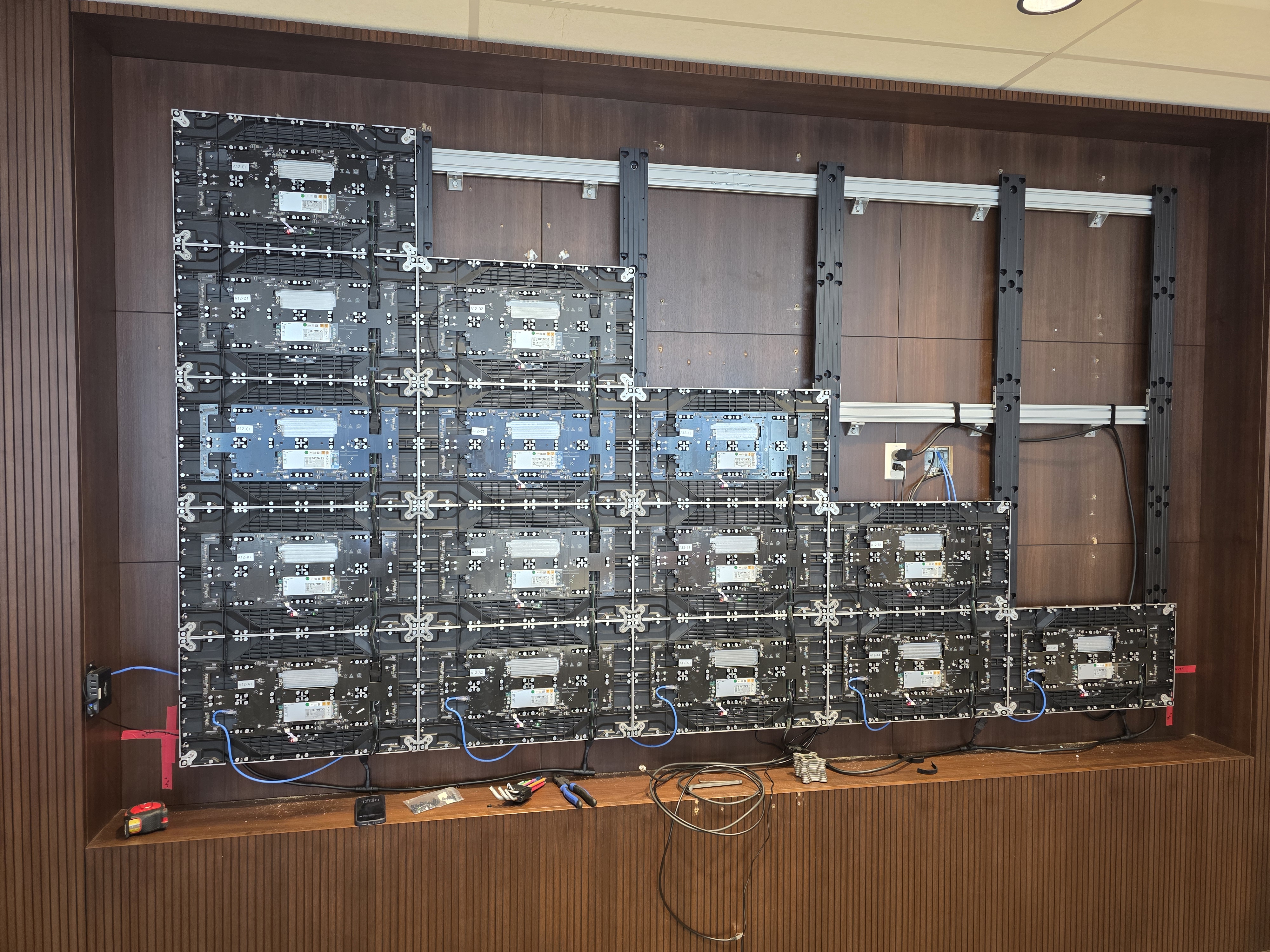 A Direct View LED video wall mid-installation, with position-labelled cabinets mounted to the structural rail system