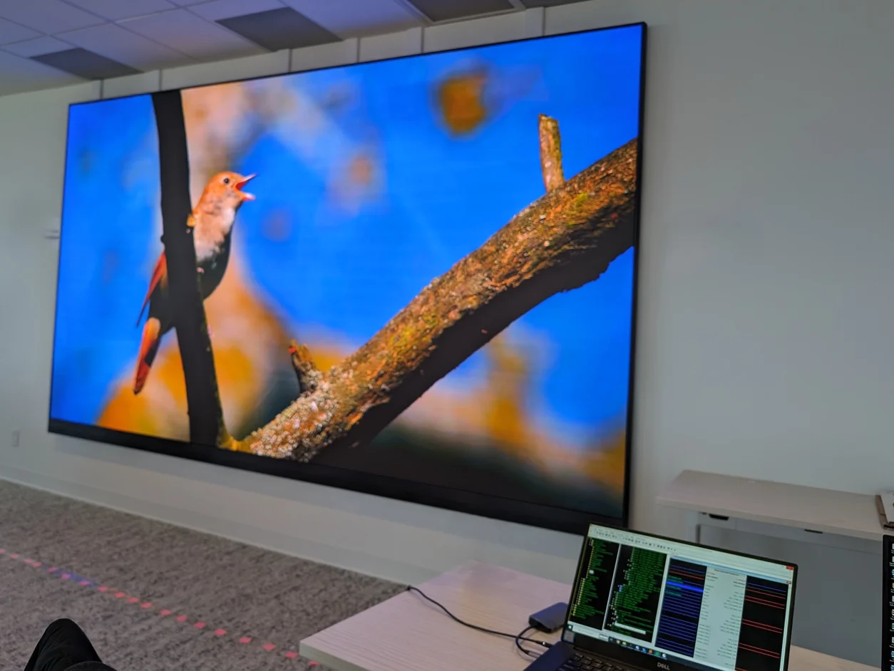 A Direct View LED video wall running live content in a meeting room, with a laptop in the foreground showing the calibration and programming file