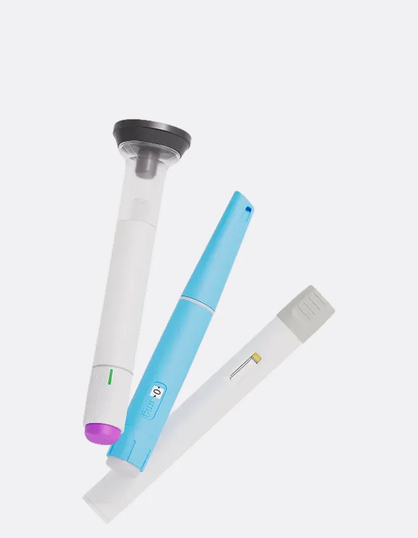 Three medical testing devices on a white background: a white and purple lancet, a blue insulin pen with a dosage indicator, and a white blood glucose test strip.