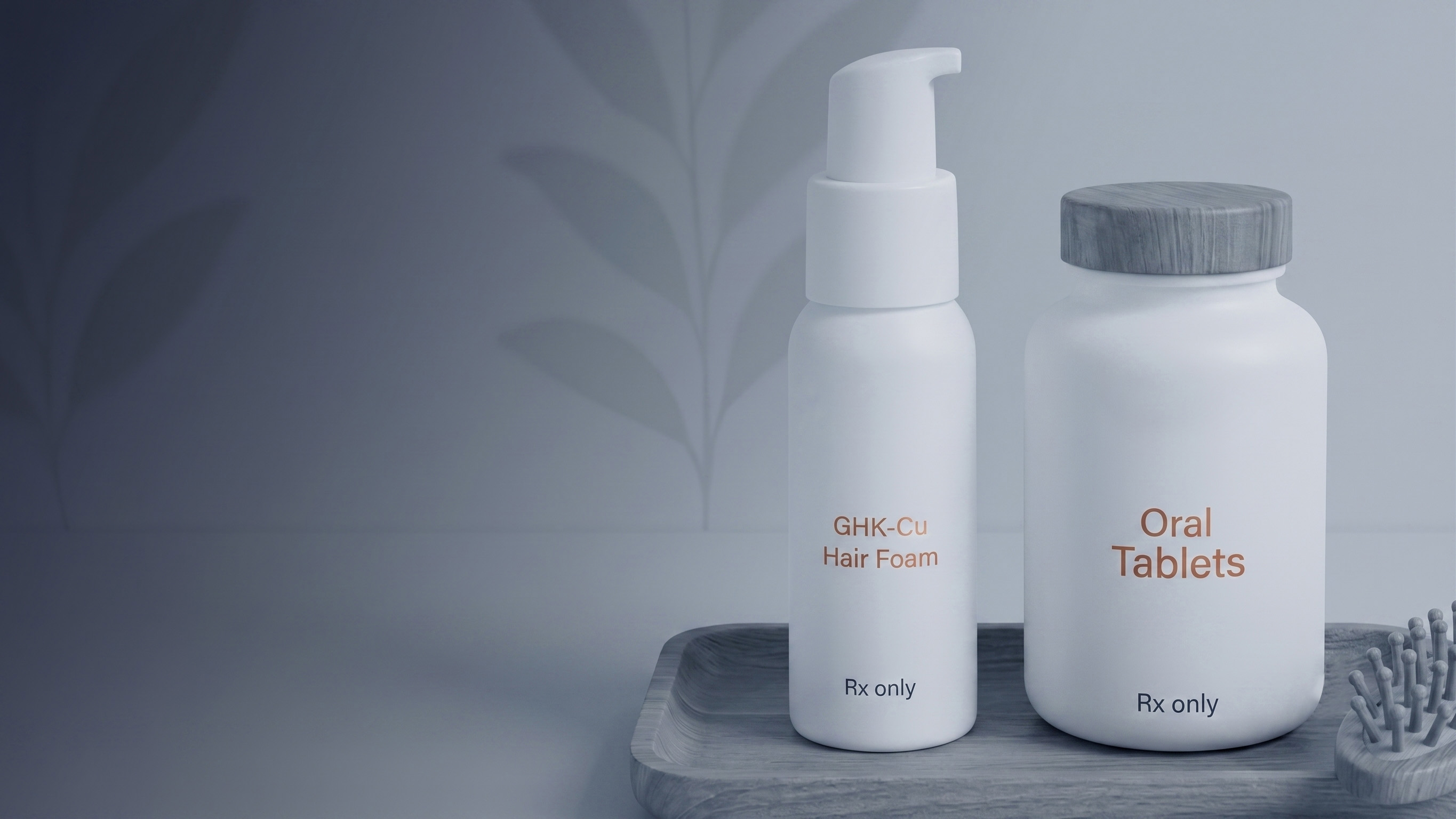 Two white bottles labeled GHK-Cu Hair Foam and Oral Tablets, both marked Rx only, placed on a wooden tray next to a hairbrush with a grey wooden handle, against a subtle leafy patterned blueish-gray background.