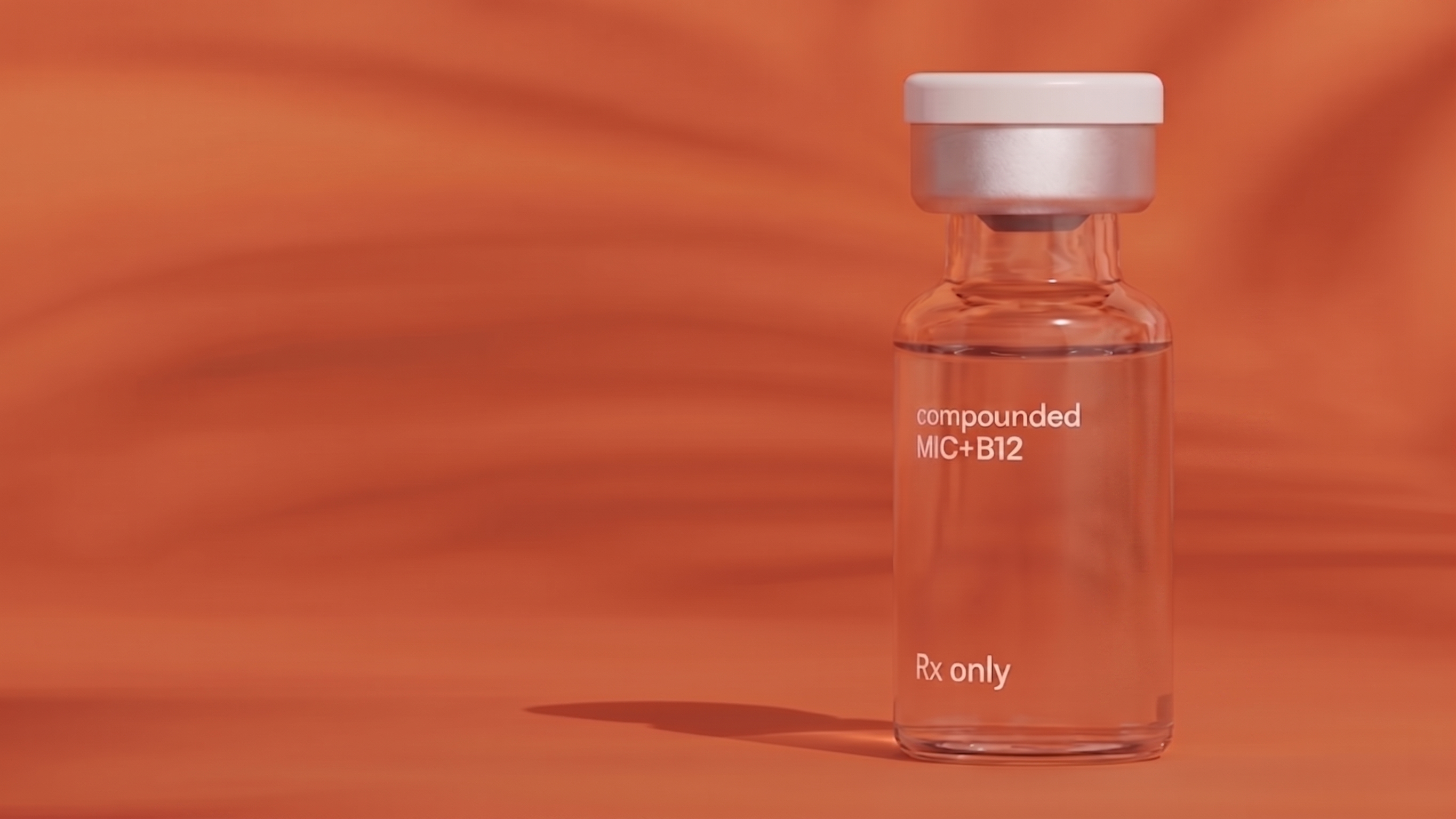 Clear glass vial with a silver cap against an orange background, labeled 'compounded MIC+B12' and 'Rx only'.