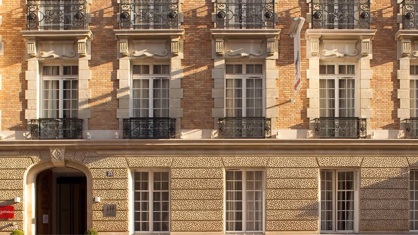 Façade d'un bâtiment en brique avec fenêtres décoratives et balcons en fer forgé.