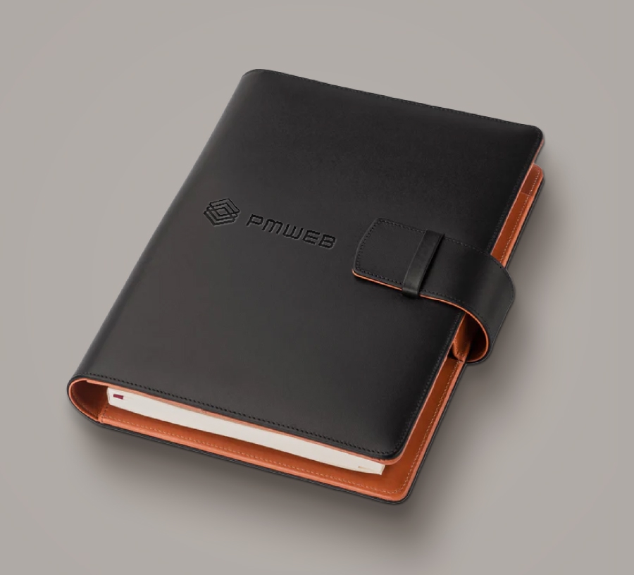 Closed black leather planner with pmweb logo embossed on cover and brown interior lining.