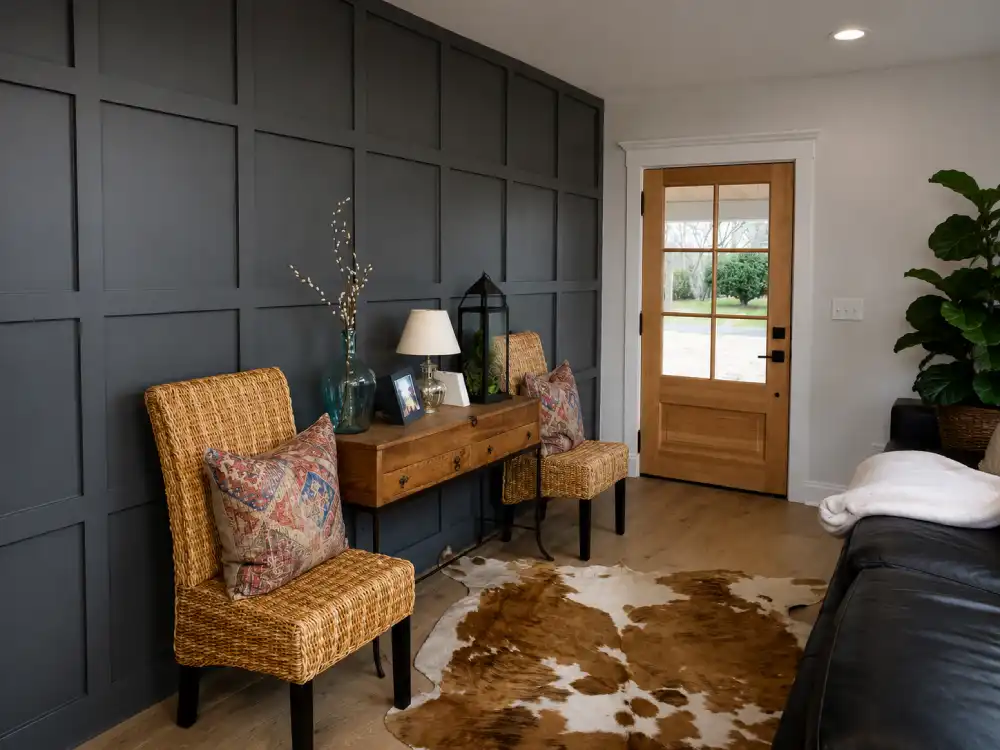 Home entryway with a dark paneled accent wall, wicker chairs, console table, and wood front door
