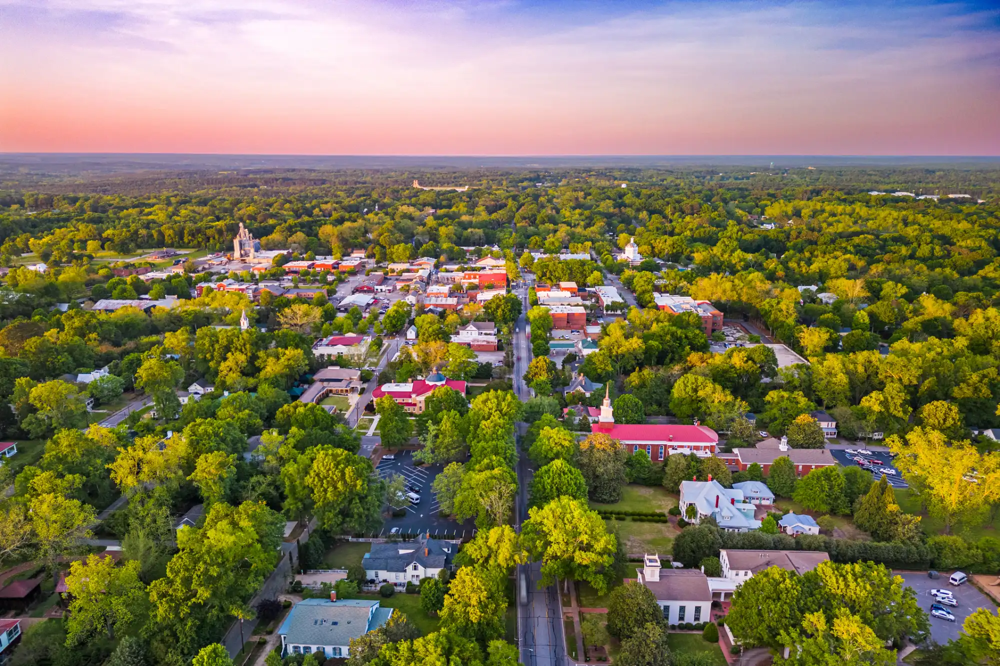 Aerial view of a historic Georgia downtown with tree-lined streets at sunset